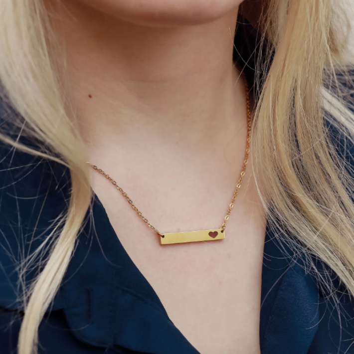 Gold necklace with a bar pendant on a person.